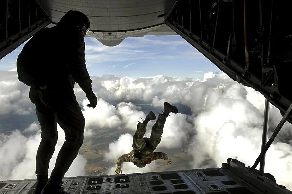 Pararescuemen jump out the back of a C-130 Hercules