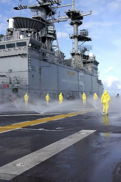 Personnel conduct Aqueous Film Forming Foam testing on the flight deck of USS Bataan