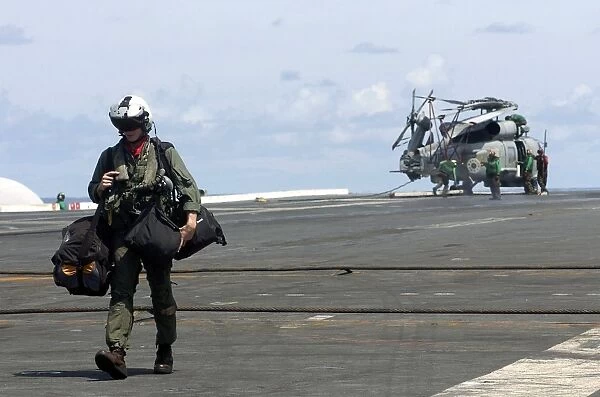A pilot walks across the flight deck of USS Kitty Hawk