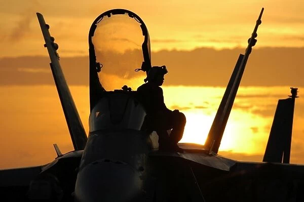 A plane captain enjoys a sunset from atop an F  /  A-18 Hornet