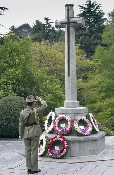Representative of the Australian Defense Force salutes a cross after laying a wreath