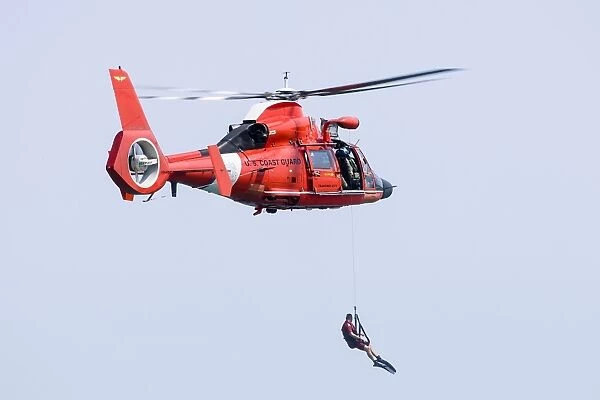 A rescue swimmer is lowered from a U. S. Coast Guard HH-65 Dolphin helicopter