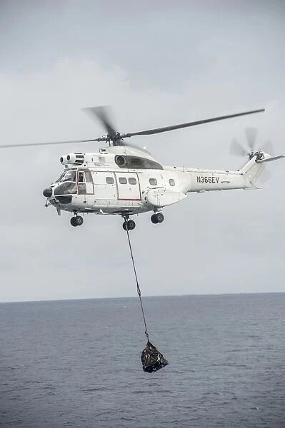 An SA-330 Puma transport helicopter moves cargo during a vertical replenishment