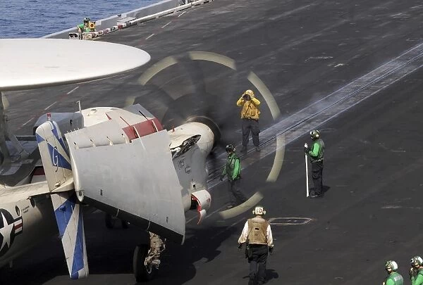 A Sailor directs an E-2C Hawkeye to the catapult aboard the USS Dwight D. Eisenhower