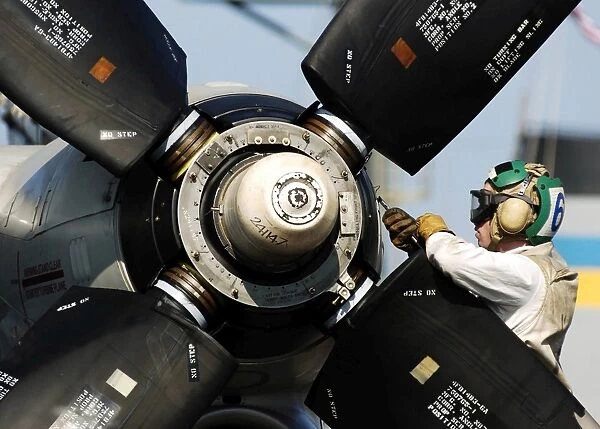 A Sailor performs maintenance on the propeller of an E-2C Hawkeye