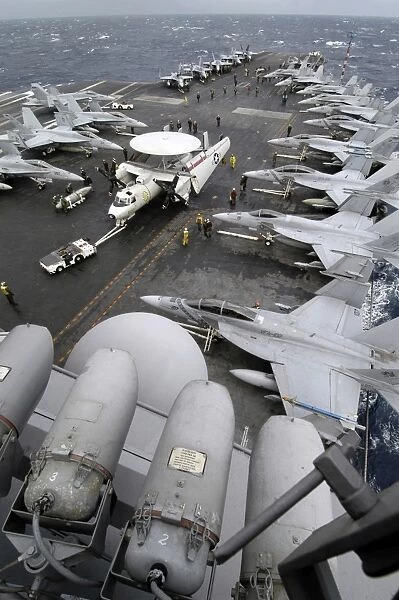 Sailors move an E-2C Hawkeye down the crowded flight deck aboard USS Kitty Hawk