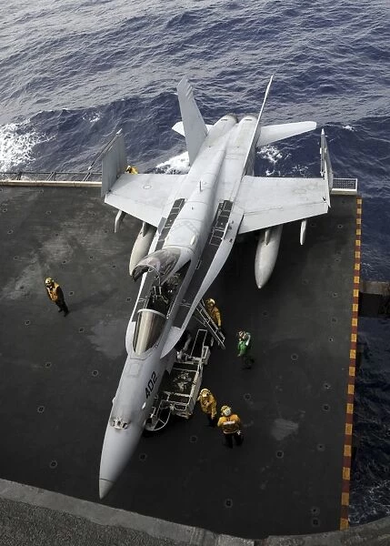 Sailors move an F  /  A-18C Hornet into the hangar bay