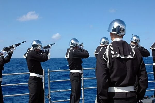 Sailors fire a gun salute during a burial-at-sea