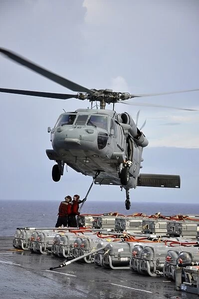 Sailors hook an ammunition pallet to an MH-60S Sea Hawk helicopter