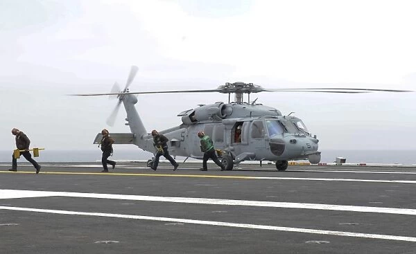 Sailors leave the landing area of an HH-60H Sea Hawk helicopter