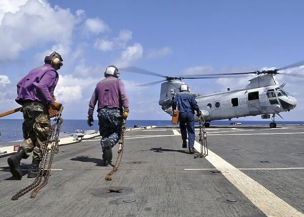 Sailors rush to chock and chain a CH-46E Sea Knight helicopter
