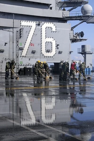 Sailors scrub the flight deck aboard the aircraft carrier USS Ronald Reagan