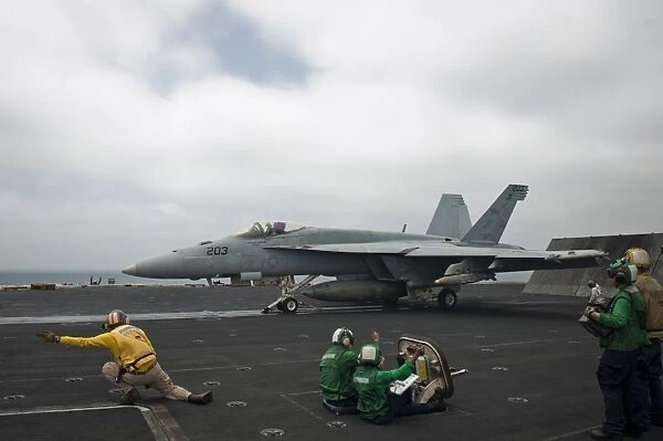 Sailors signal to launch an F  /  A-18E Super Hornet