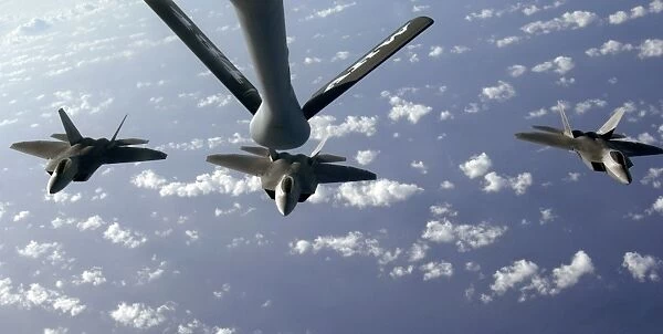 A three ship formation of F-22 Raptors move into refueling position