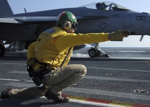 A shooter signals the launch of an F  /  A-18 Super Hornet