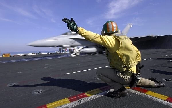 A shooter signals the launch of an F  /  A-18 Super Hornet