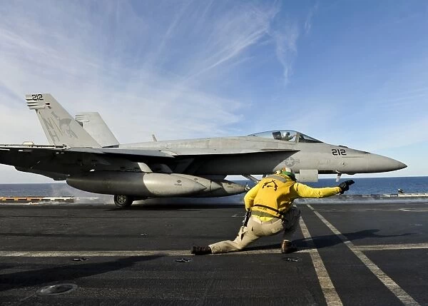 A shooter signals to launch an F  /  A-18E Super Hornet aboard USS Nimitz