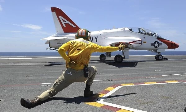 Shooter signals to a T-45C Goshawk as it launches from USS George H. W. Bush