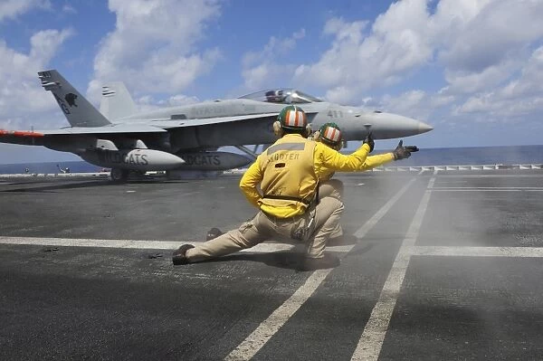 Shooters give the signal to launch an F  /  A-18C Hornet