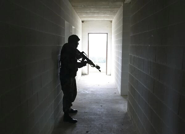 A soldier clears a hallway in a building at a Military Operation in Urban Terrain