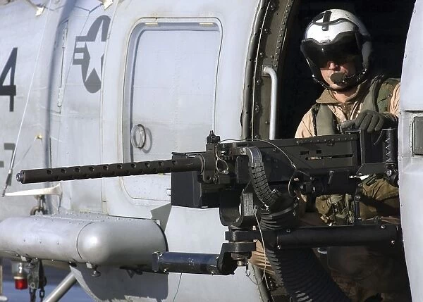Soldier mans a. 50 caliber machine gun on an SH-60 Seahawk