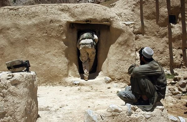A soldier from the National Guard searches the home of a suspected Taliban member