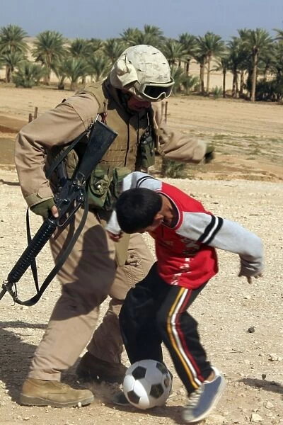 A soldier plays soccer with an Iraqi boy