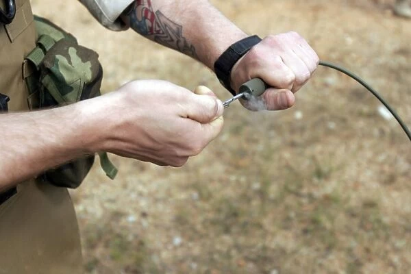 A soldier pulls a detonation cord igniter to start a reaction detonating C-4 explosives