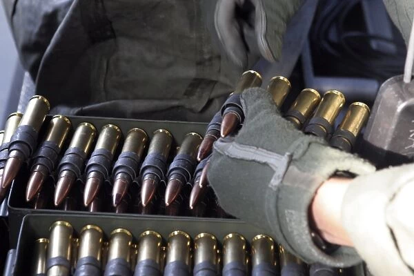 A soldier reaches for a belt of. 50 caliber ammunition