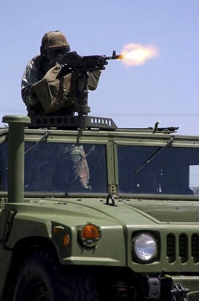 Soldier shoots a M-240B machine gun atop a humvee