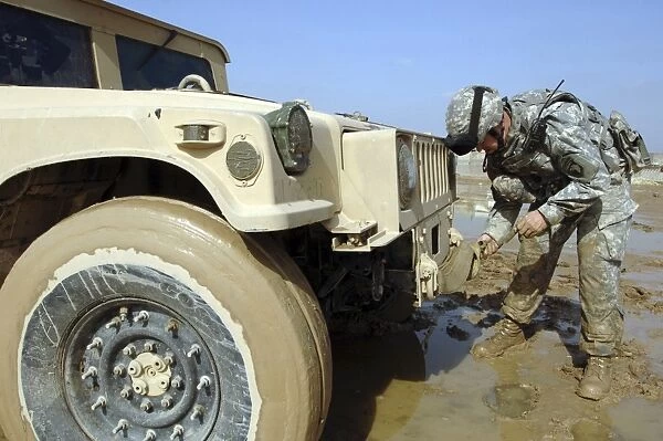Soldier unties a rope to tow a humvee out of the mud