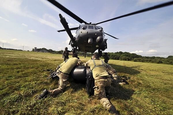 Soldiers mount an inflatable Zodiac boat to the bottom of a HH-60 Pave Hawk