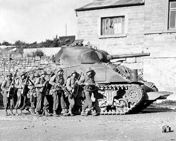 Soldiers and their tank advance into a Belgian town during WWII