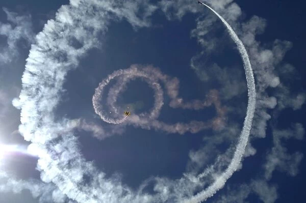 A stunt plane flies around a parachutist