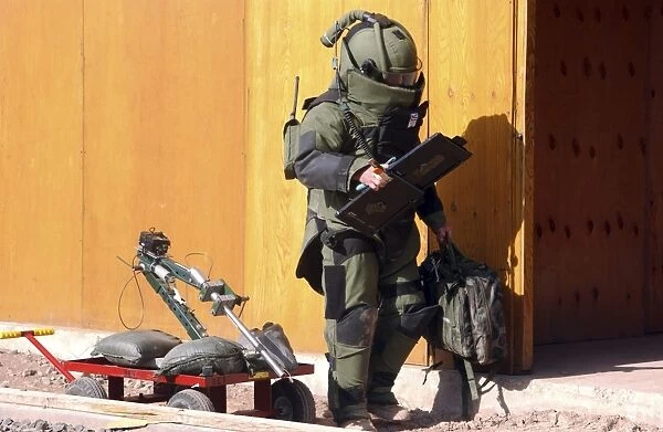 A technician from a Navy Explosive Ordnance Disposal Mobile Unit holding equipment