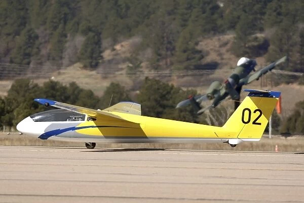A TG-10B glider lifts into the air as it is towed down the runway