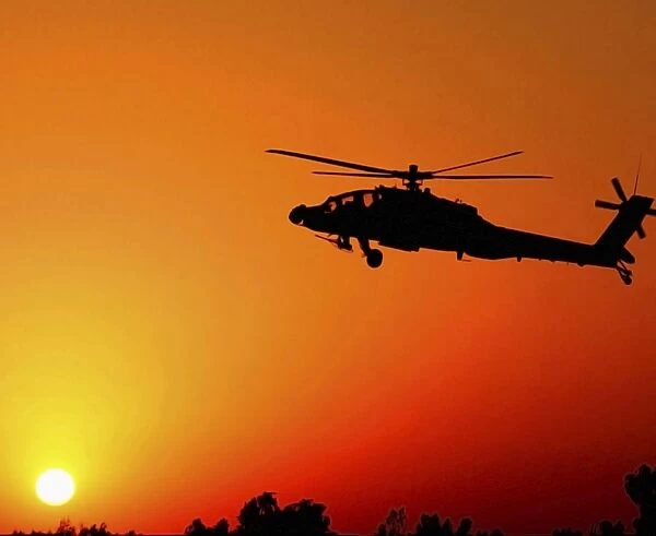 A U. S. Army AH-64 Apache Helicopter prepares to land as the sun comes up