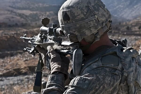 U. S. Army sniper scans a village in Afghanistan for Taliban activity