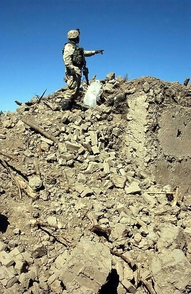 A U. S. Army Soldier examines the rubble of a destroyed compound