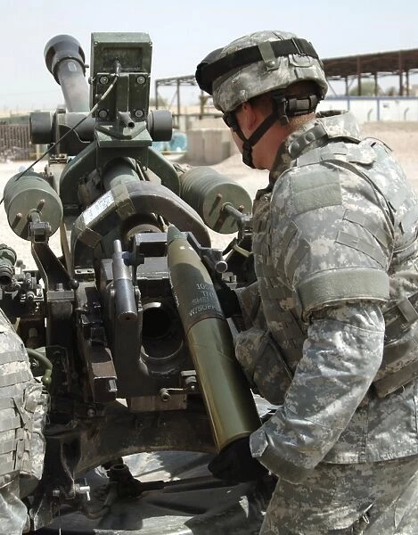 U. S. Army Soldier loads a 105mm artillery round into a M119 Howitzer