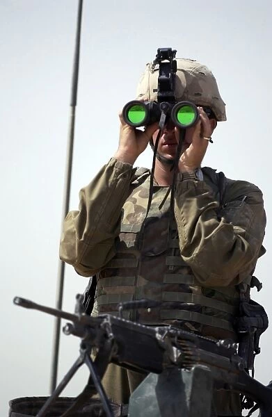 U. S. Army Specialist uses binoculars to scan the perimeter
