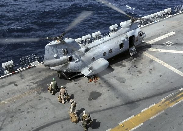 U. S. Marines board a CH-46 Sea Knight helicopter on the flight deck of USS Peleliu