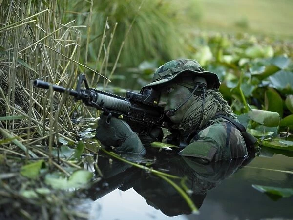 U. S. Navy SEAL crosses through a stream during combat operations