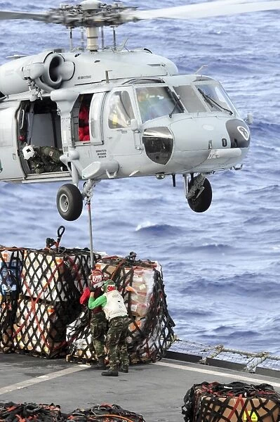 U. S. Sailors connect a cargo pendant to an MH-60S Seahawk helicopter
