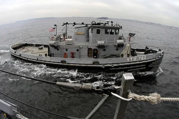A Yokosuka Naval tugboat prepares to assist the guided missile destroyer USS Curtis