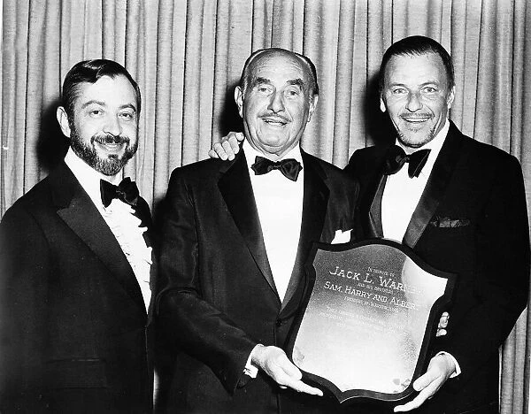 Frank Sinatra with friends holding a shield to tribute the Warner Brothers