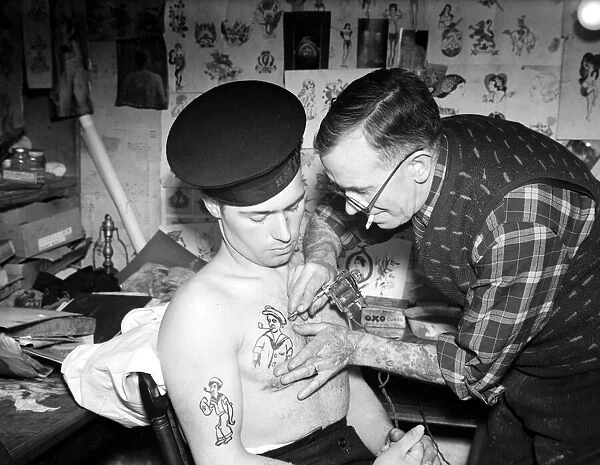 Tattooist applying sailor tattoo to the chest of a sailor on the Royal Navy Circa 1945