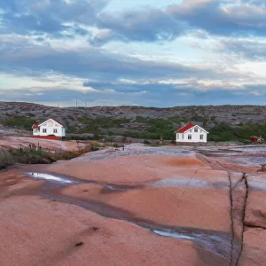 Three isolated houses on red granite island at dusk, Bohuslan, Vastra Gotaland, West Sweden, Sweden, Scandinavia, Europe