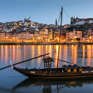 Traditional Rabelo boat designed to carry wine down Douro river with city skyline behind