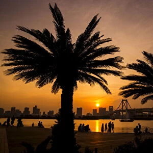 People mingle at Odaiba beach as sun sets over Tokyo Bay in Tokyo